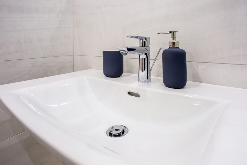 Soap and shampoo dispensers on Water tap sink with faucet in expensive loft bathroom